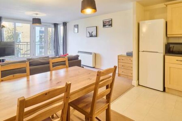 A modern kitchen with a dining table and chairs, a refrigerator, and a view of the outdoors. - Host Stay Bingley Court (Canterbury)