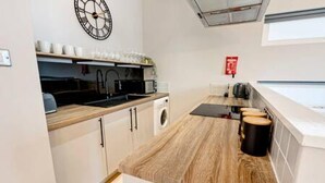 A compact kitchen with a wooden countertop, a sink, a microwave, and a small washing machine. - Host Stay Ropewalks Quarters V (Liverpool)