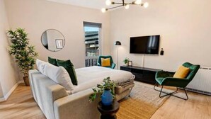 A modern bedroom with a bed, a green armchair, a TV, and a plant. - Host Stay Ropewalks Quarters V (Liverpool)