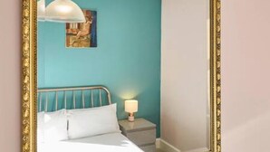 Une chambre à coucher avec un lit, une table de chevet, une lampe et un tableau au mur.