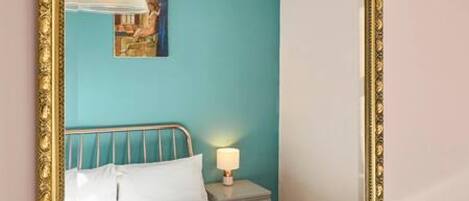 Une chambre à coucher avec un lit, une table de chevet, une lampe et un tableau au mur.