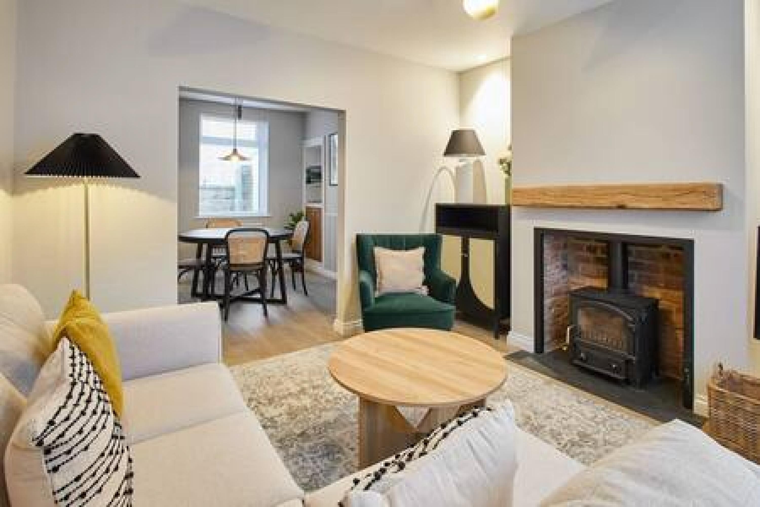 A cozy living room with a fireplace, a sofa, a coffee table, and a lamp.
