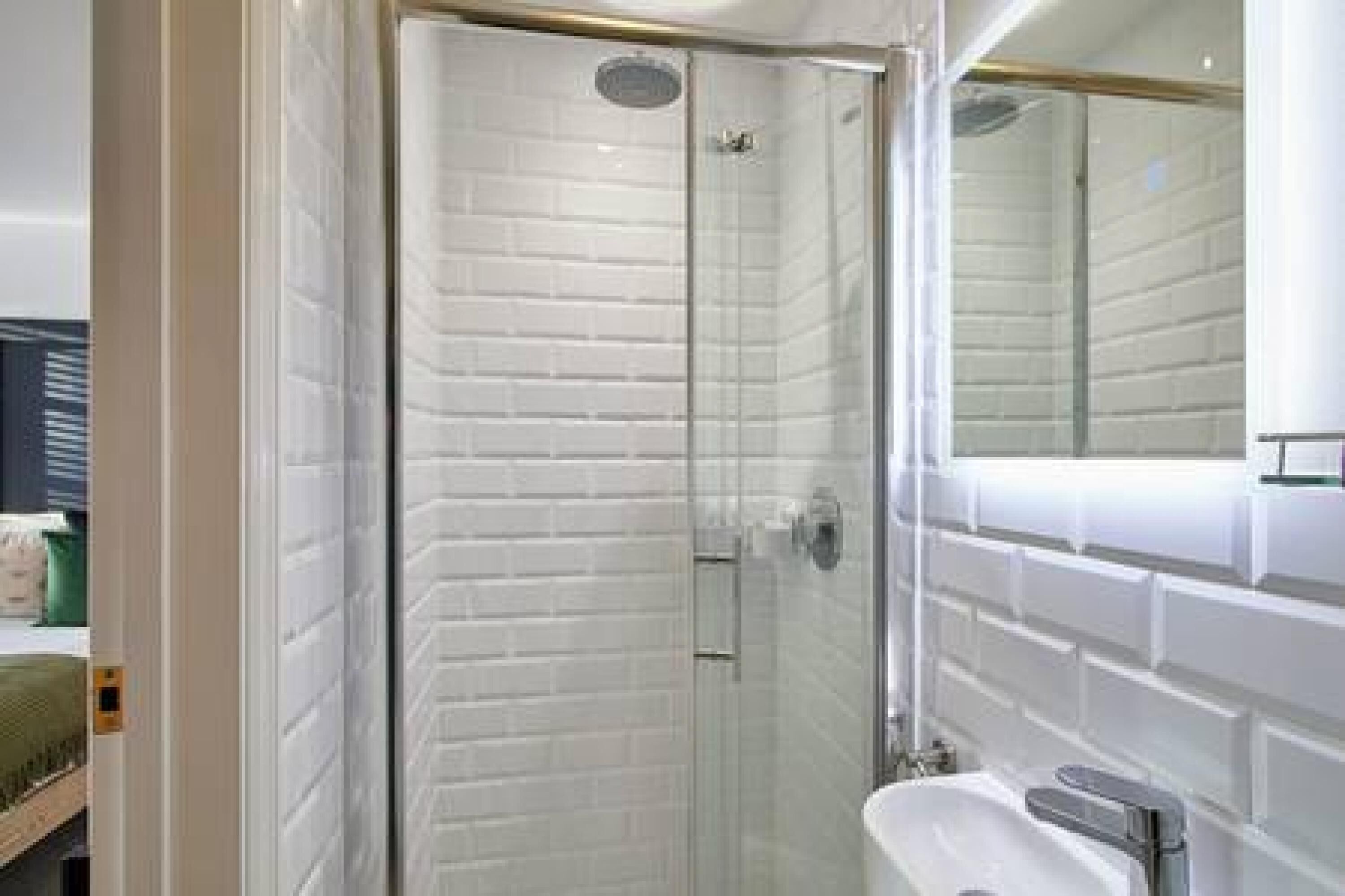 A modern bathroom with a glass shower enclosure, a white sink, and a mirror above the sink.