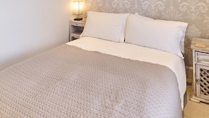 A neatly made bed with a textured blanket, a bedside lamp, and a framed picture on the wall. - Host Stay Sail Away (Whitstable)