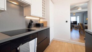 A modern kitchen with a black countertop, white cabinets, and a built-in oven. - Host Stay Herbert Road (Ramsgate)