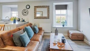 Un salon moderne avec un canapé en cuir, une table basse et une vue sur la cuisine.