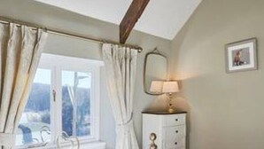 Una camera da letto con un letto, un comodino, una lampada e una finestra con tende.