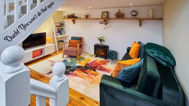 A living room with a sofa, a television, a coffee table, and a bookshelf. - Host Stay Millers Coach House (Hexham)