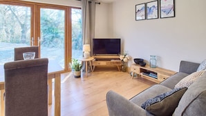 Ett modernt vardagsrum med TV, soffa och matplats.