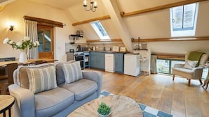 A modern loft-style living space with a kitchen, dining area, and a cozy seating area. - Host Stay Llewenau Draw Barn (Crickhowell)