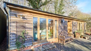 A wooden cabin with a glass door, a bench, and potted plants. - Host Stay Orchard Barn (Ashford)