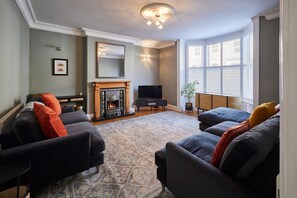 A living room with a fireplace, sofas, a TV, and a large window with blinds. - Host Stay Mollymac Ground Floor (Saltburn-by-the-Sea)