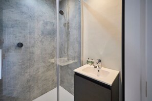 A modern bathroom with a glass-enclosed shower, a white sink, and a dark cabinet. - Host Stay Mollymac Ground Floor (Saltburn-by-the-Sea)