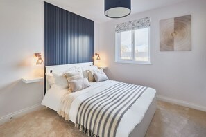 Un dormitorio con cama, lámparas de noche, una ventana y una obra de arte en la pared.