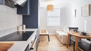 Une cuisine moderne avec un poêle noir, des armoires blanches et une table à manger en bois, accompagnée de chaises.