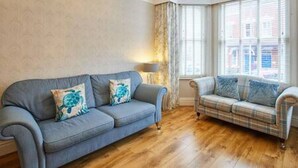 Une pièce avec un canapé bleu et un canapé à carreaux, tous deux agrémentés de coussins décoratifs.
