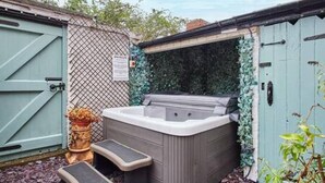 Un bain à remous avec des marches menant à l’intérieur, entouré d’une clôture et d’un abri de jardin.