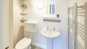 Ein kleines Badezimmer mit Toilette, Waschbecken und Handtuchhalter.