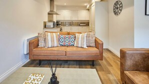 Una sala de estar moderna con un sofá, una mesa de centro y una cocina al fondo.