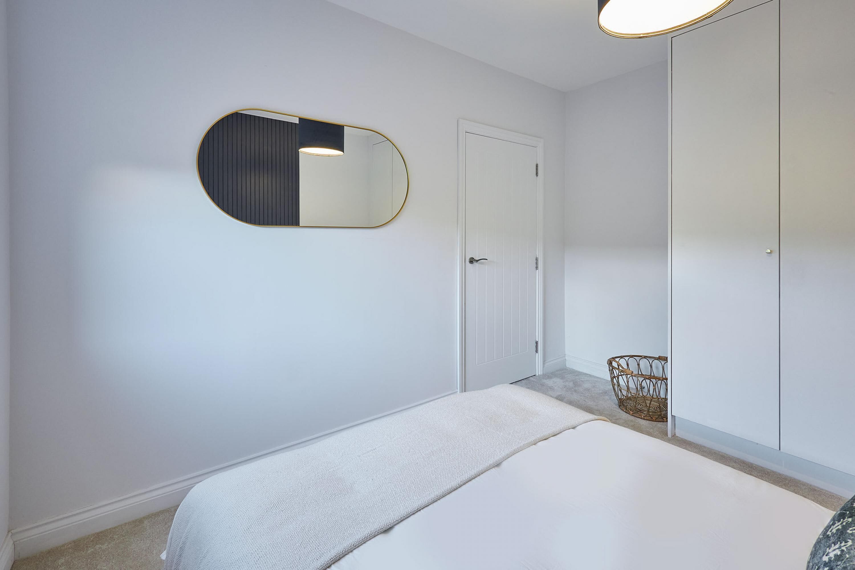 A bedroom with a bed, a door, a wardrobe, and a mirror.