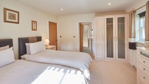 A bedroom with two beds, a wardrobe, a bathroom, and a mirror.