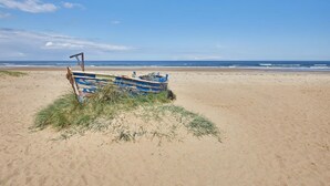 A boat on a sandy beach with the ocean in the background. - Host Stay The Beach House (Redcar)