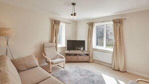 A modern living room with a sofa, armchair, TV, and windows with curtains. - Host Stay 57 Woodland View (Holmfirth)