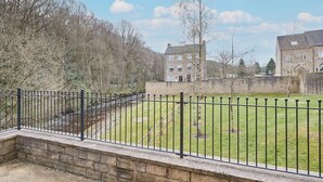 A courtyard with a stone wall, a grassy lawn, and a metal fence. - Host Stay 57 Woodland View (Holmfirth)