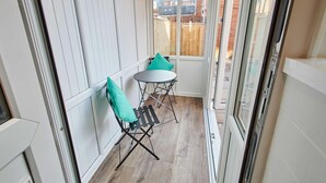 A narrow balcony with a small table and chairs, a view of a wooden fence and buildings, and a white door. - Host Stay Station View (Saltburn-by-the-Sea)