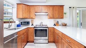 A modern kitchen with wooden cabinets, stainless steel appliances, and a white countertop.