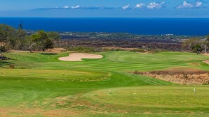 A golf course with a view of the ocean and distant land.