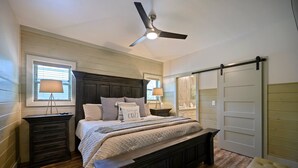 A bedroom with a large bed, wooden headboard, bedside tables, a ceiling fan, and a sliding door closet.