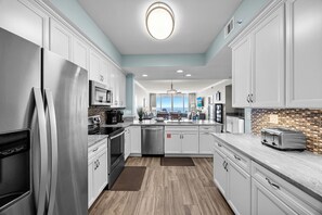 A modern kitchen with white cabinetry, a stainless steel refrigerator, a microwave, and a toaster.