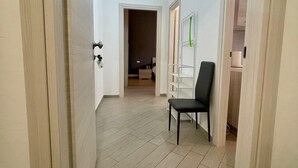 A hallway with a chair, a coat rack, and a door leading to a room. - Il Buon Risveglio Agropoli (Agropoli)