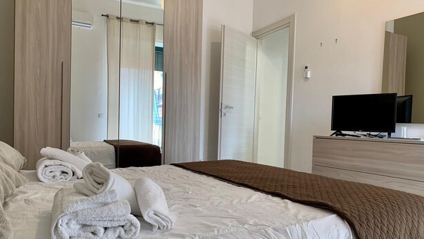 A hotel room with a bed, a TV, a wardrobe, and a mirror. - Il Buon Risveglio Agropoli (Agropoli)
