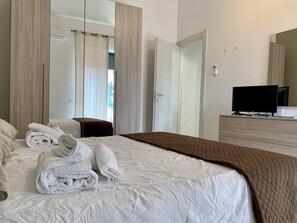 A hotel room with a bed, a TV, a wardrobe, and a mirror. - Il Buon Risveglio Agropoli (Agropoli)