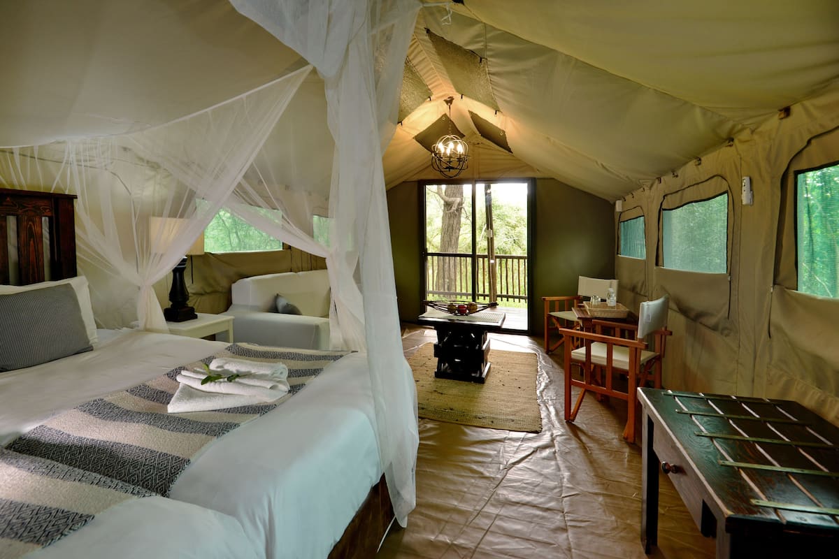A tented room with a bed, a table, and chairs.
