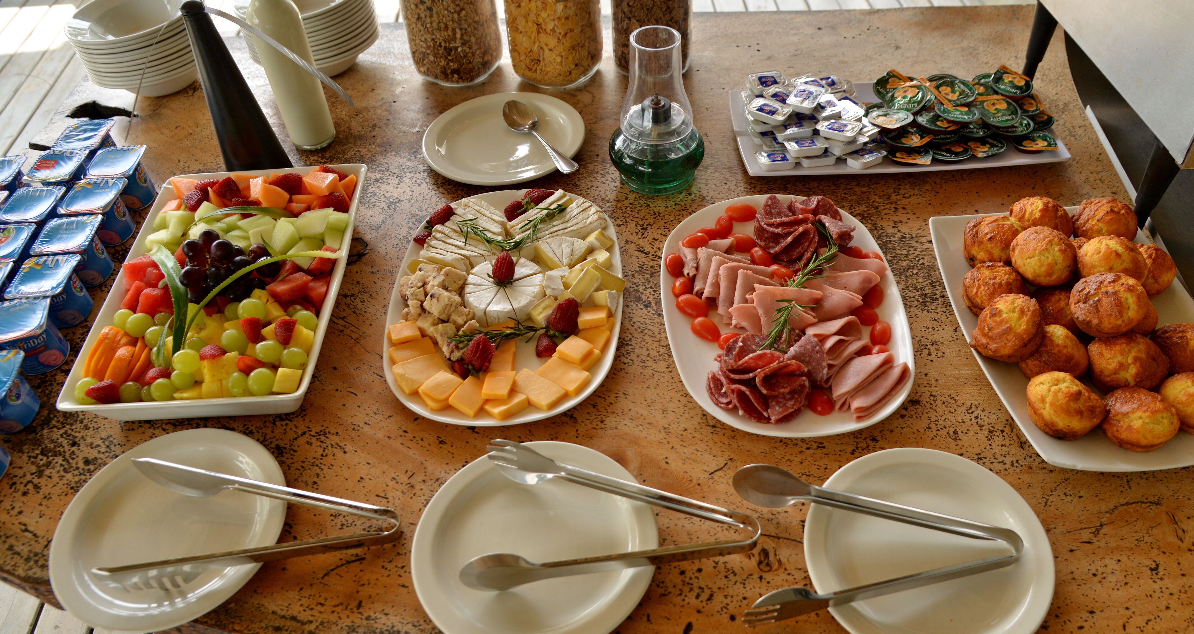A buffet table with various food items including fruits, cheeses, meats, and pastries.