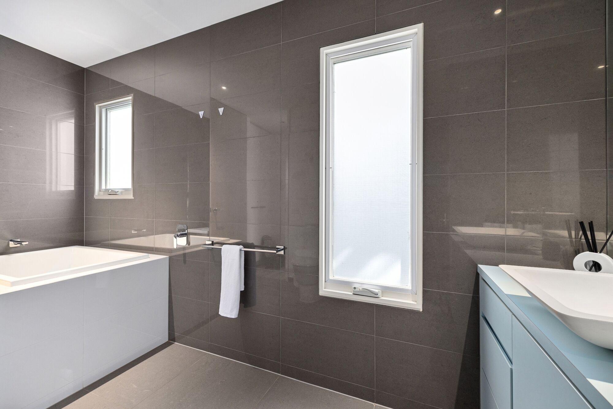 Een moderne badkamer met twee wastafels, een grote spiegel en een raam.