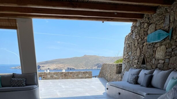 Un espace extérieur aménagé, abrité et doté d’un mur en pierre, offrant une vue sur la mer.