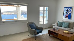 Un salon avec vue sur la mer, comprenant un canapé, un fauteuil et une table basse.