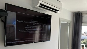 A wall-mounted TV with a message about card expiration, an air conditioning unit, and a door leading to a balcony.