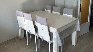 A dining area with a white table and chairs, a wardrobe, and a door with a textured panel.
