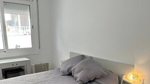 A bedroom with a bed, a nightstand, a lamp, and a window.