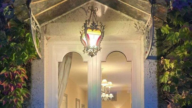A white door with a glass panel, a chandelier inside, and ivy on the walls. - Le Clos des Tilleuls - Gite 10 people (Francueil)