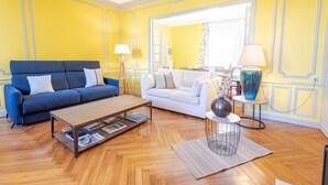 A living room with a blue sofa, a white sofa, a coffee table, and a lamp on a side table. - Le Clos des Tilleuls - Gite 10 people (Francueil)