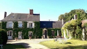 A two-story house with ivy-covered walls, a gravel driveway, and a small garden with outdoor seating. - Le Clos des Tilleuls - Gite 10 people (Francueil)