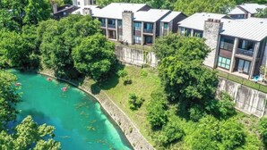 A multi-story hotel with balconies, a river view, and a stone facade. - CW C113 Comal Vista (New Braunfels)