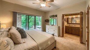A bedroom with a large bed, a dresser, a vanity with a mirror, and a ceiling fan. - CW C113 Comal Vista (New Braunfels)