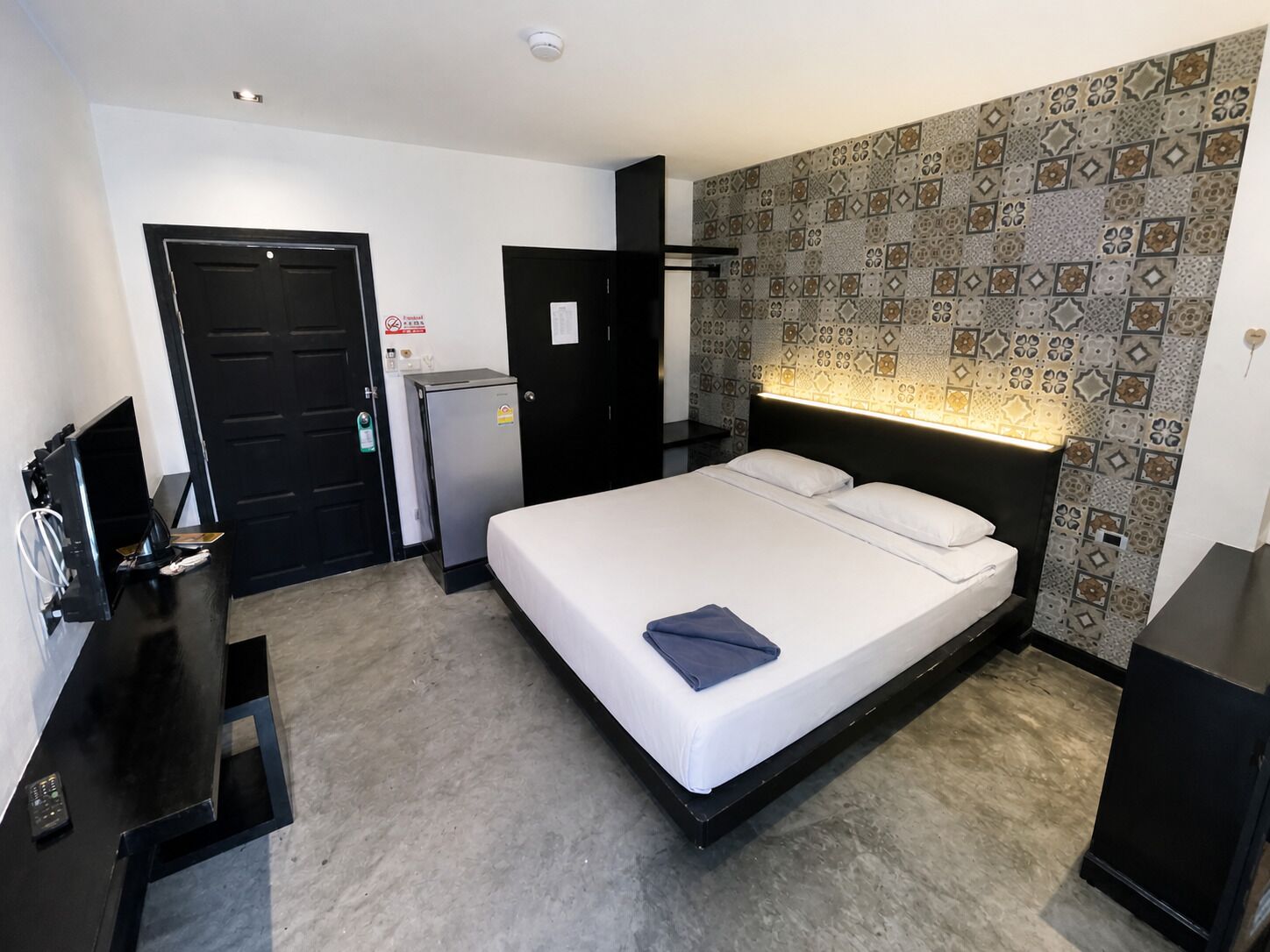 Ein Hotelzimmer mit Bett, Schreibtisch, Kühlschrank und einer Tür.